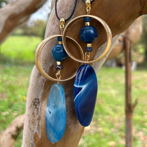 Collier avec grande agate bleue ovale dans cercle doré et surmonté d'une perle bleue. Lien cuir agneau cousu