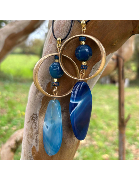 Collier avec grande agate bleue ovale dans cercle doré et surmonté d'une perle bleue. Lien cuir agneau cousu